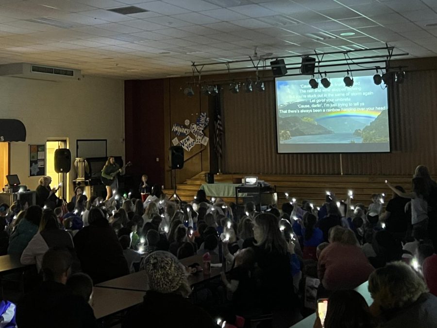 Junior Karli Blood and pre-schooler Muriel LaCoss sing Rainbow by Kacey Musgraves, to the whole elementary at the PBIS assembly on January 6th, 2023. Students were given finger lights to light up the crowd.
