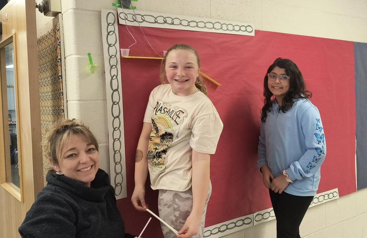 A group of BMU 4th graders sets up a bulletin board in the elementary hallway on February 7th, 2024. This is an interactive display used to teach students about gravity.