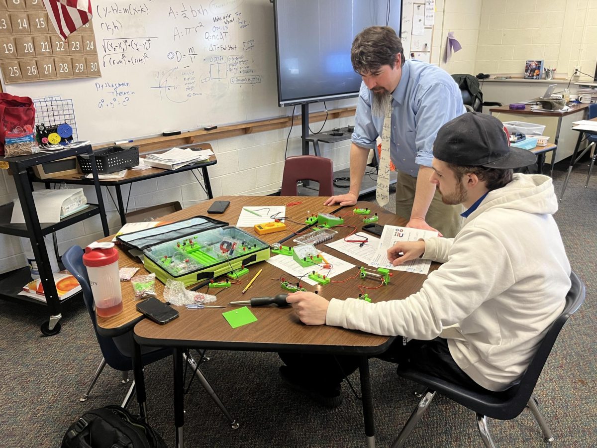 STEM Teacher Forest Matthews with Beau Tattersall on March 1st, 2024. Tattersall was using a volt meter to measure the voltages and amps the batterys are putting off to the light bulb. 