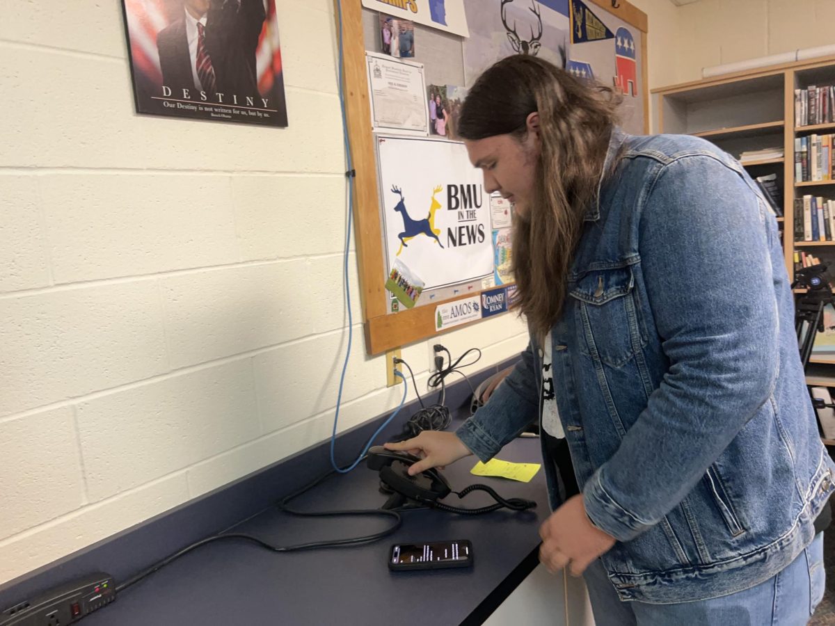 Blue Mountain Union School sophomore, Paxton Hosmer, reaches for the phone to broadcast the morning announcements on Friday, October 4, 2024 in Wells River, Vermont. This is his first year broadcasting for the school after the previous announcer graduated. 