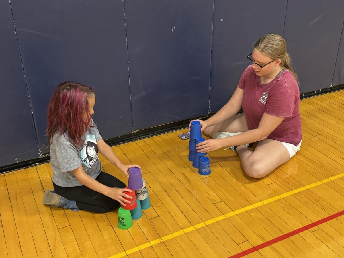 Blue Mountain freshman Abigail Mitchell teaches second grader Mya Tinkham  how to cup stack in P.E. on Thursday, October 3, 2024.