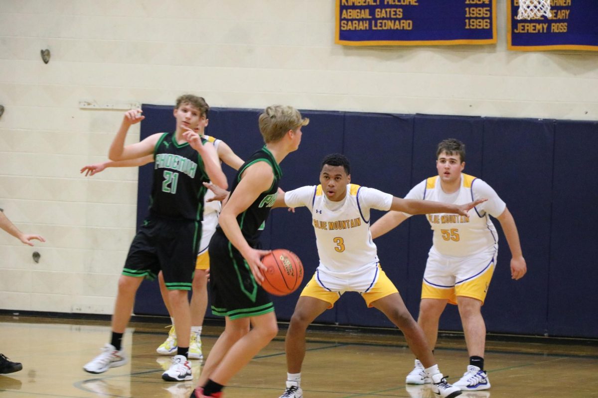 Brody Scott (behind a player), Jamal Saibou, and Jacob Roberts on zone defense against the Phoenixes in the Dr. Harry M. Rowe Gymnasium, Wells River, VT.