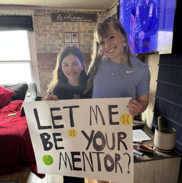 Ainsley Kendall with her mentee Harmony Scott posing for a photo with Scott's mentor poster