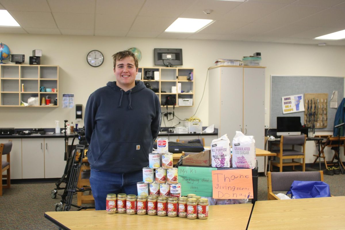 Student council member, Jacob Roberts, stands next to Thanksgiving Food Drive donations.